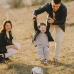 parenting Family enjoying playful soccer game outdoors, capturing joyful moments.