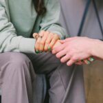 mental Close-up of two people holding hands during a comforting therapy session.