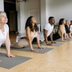 A group of adults performing yoga poses on mats indoors, emphasizing diversity and wellness.